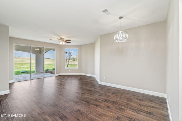 unfurnished room featuring baseboards, visible vents, dark wood-style floors, and ceiling fan with notable chandelier