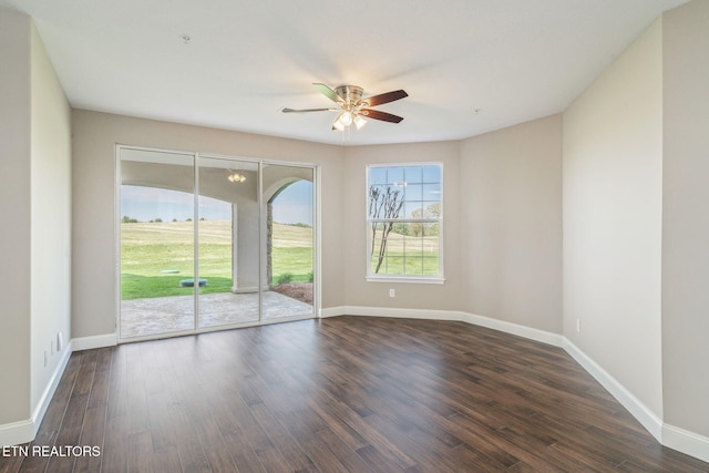 empty room featuring baseboards, ceiling fan, and dark wood-style floors