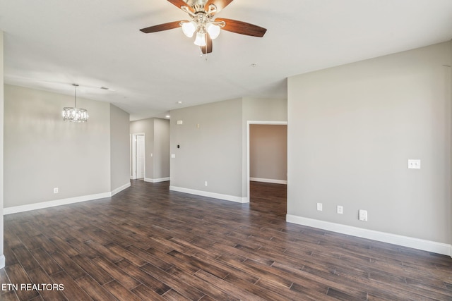 spare room with dark wood-style flooring, baseboards, and ceiling fan with notable chandelier