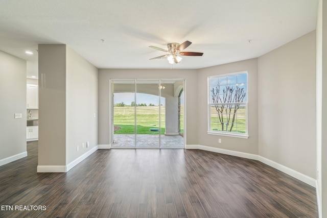 empty room featuring baseboards, dark wood-style flooring, and ceiling fan
