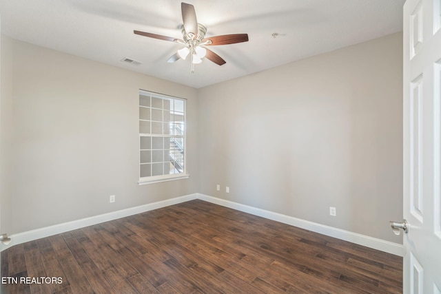 empty room with visible vents, a ceiling fan, dark wood-style flooring, and baseboards