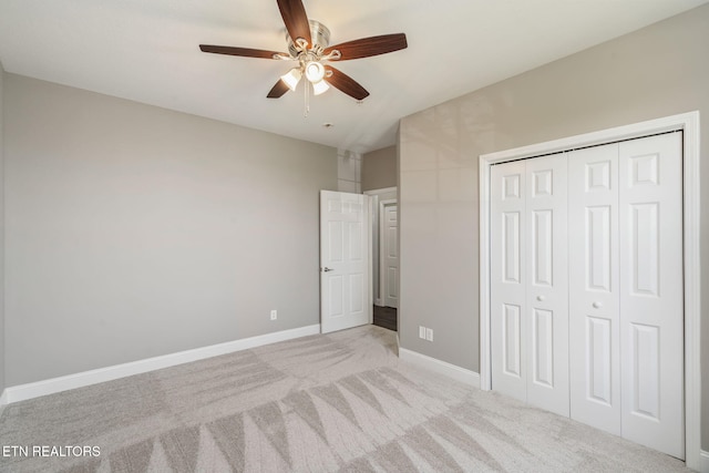 unfurnished bedroom featuring baseboards, a ceiling fan, a closet, and light colored carpet