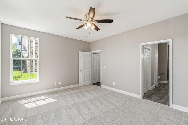 unfurnished bedroom featuring carpet flooring, a ceiling fan, baseboards, and ensuite bath