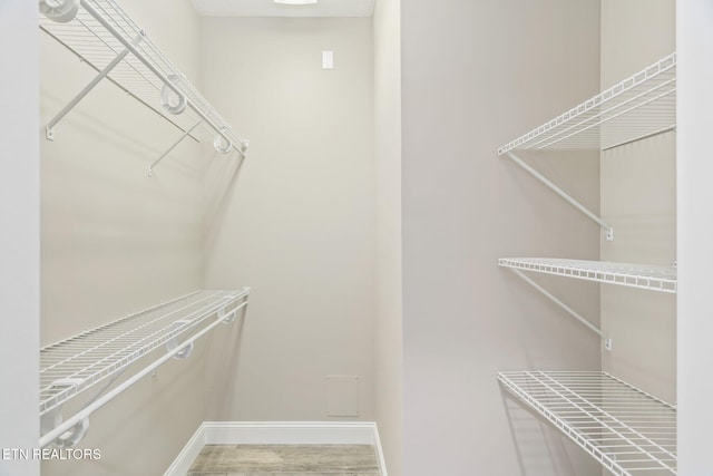 walk in closet with wood finished floors