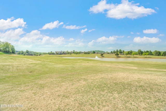 view of home's community featuring a water view, a yard, and golf course view