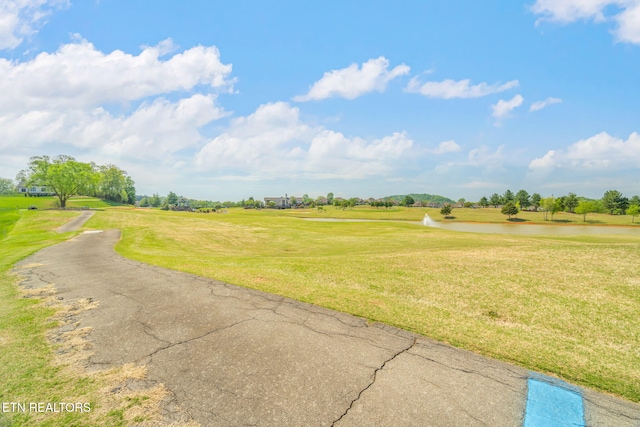 view of property's community featuring a lawn, a water view, and golf course view
