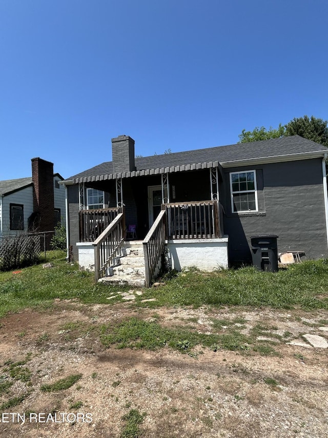 view of front of property with a porch, a chimney, and a shingled roof