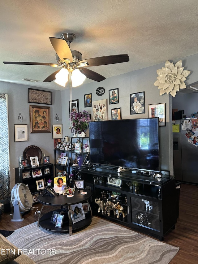 living area with a ceiling fan, a textured ceiling, and wood finished floors