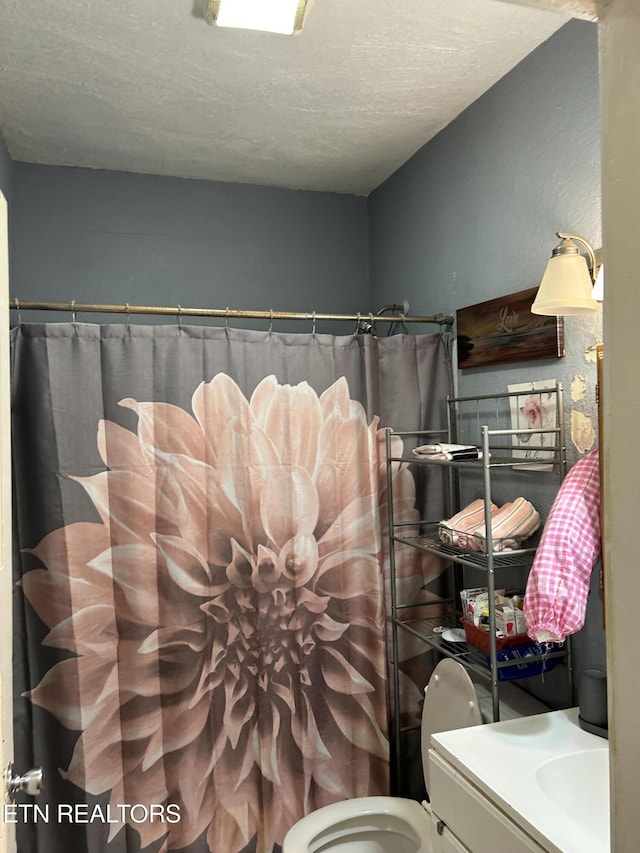 full bath with vanity, a textured ceiling, a shower with shower curtain, and toilet