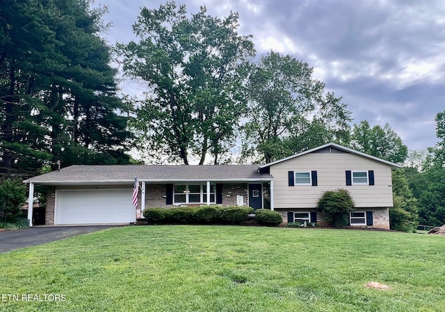tri-level home featuring an attached garage, a front lawn, driveway, and brick siding