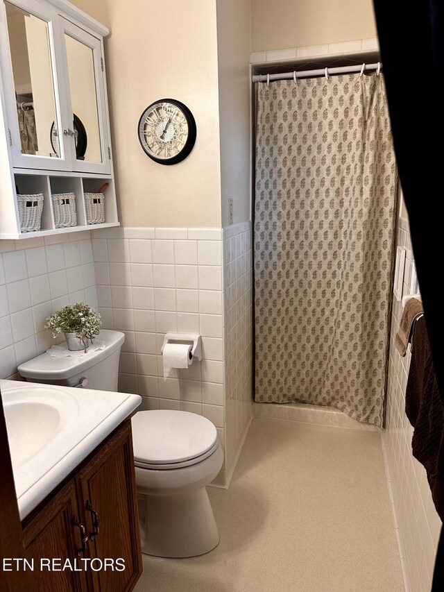 full bath with wainscoting, vanity, toilet, tile walls, and a shower with curtain
