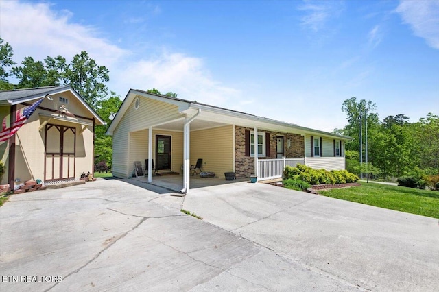 single story home with brick siding, an attached carport, a porch, a front yard, and concrete driveway