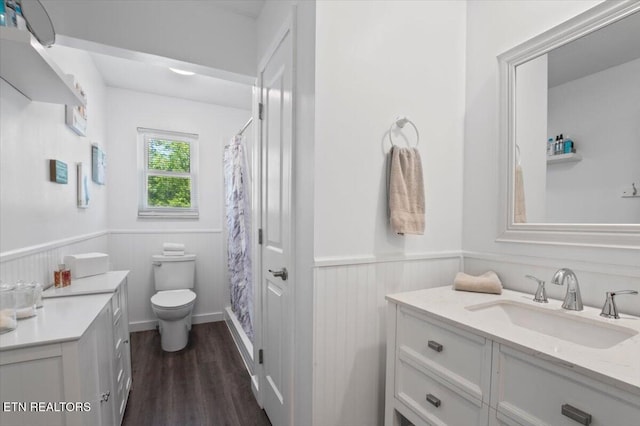 full bathroom featuring vanity, wood finished floors, curtained shower, toilet, and a wainscoted wall