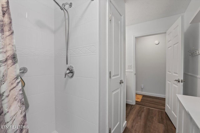 bathroom with wood finished floors and tiled shower