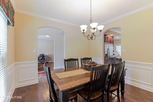 1827 Autumn Bluff Rd, Knoxville, TN 37932 - dining room featuring arched walkways, a chandelier, a wainscoted wall, ornamental molding, and dark wood-style flooring
