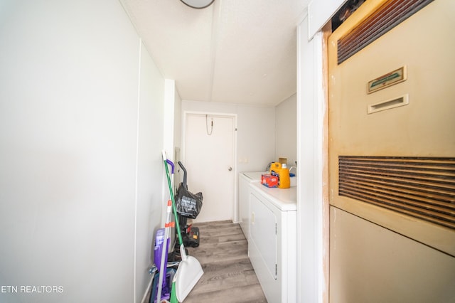 washroom featuring laundry area, a heating unit, light wood finished floors, and washing machine and dryer