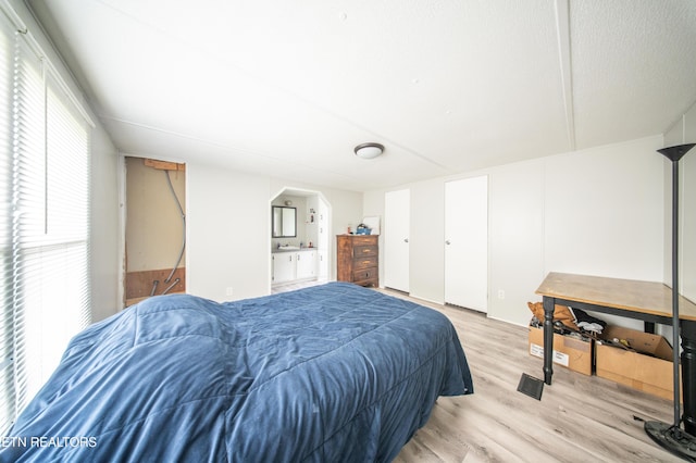 bedroom with connected bathroom and light wood finished floors