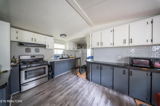 kitchen featuring white cabinets, backsplash, stainless steel appliances, and light wood-type flooring