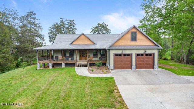 craftsman-style home featuring covered porch, driveway, metal roof, a front lawn, and an attached garage
