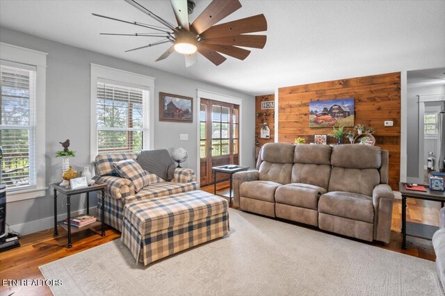 living room with a ceiling fan, baseboards, and wood finished floors