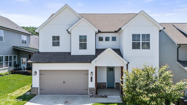modern farmhouse style home featuring a front lawn, stone siding, roof with shingles, an attached garage, and driveway