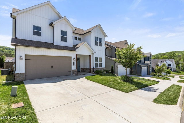 modern farmhouse featuring driveway, cooling unit, a front lawn, an attached garage, and stone siding