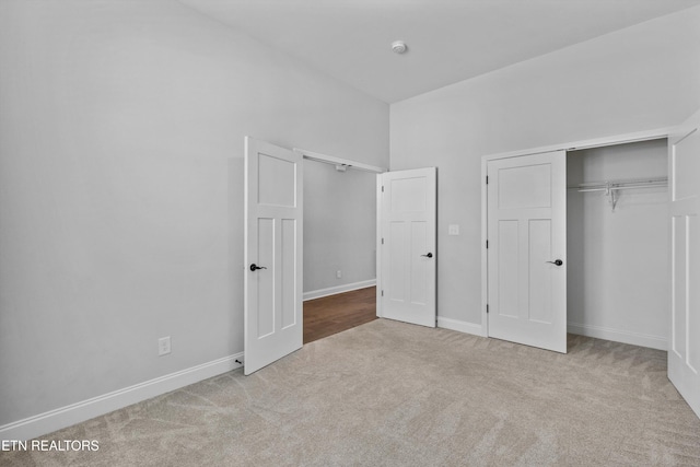 unfurnished bedroom featuring baseboards, carpet, and a closet