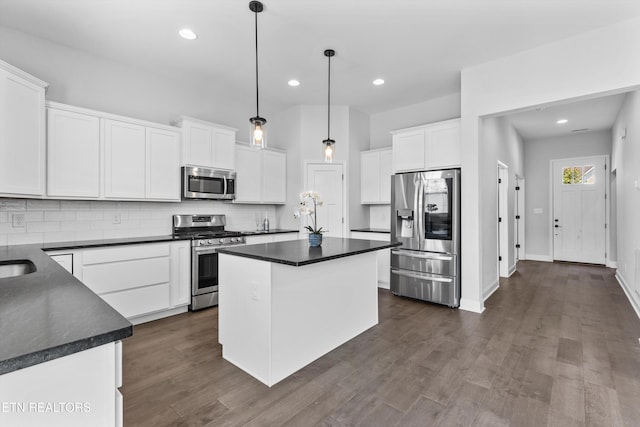 kitchen featuring dark countertops, backsplash, stainless steel appliances, and white cabinetry
