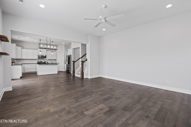 unfurnished living room with baseboards, ceiling fan, stairway, dark wood-type flooring, and recessed lighting