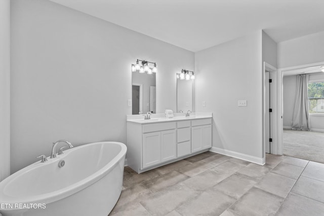 bathroom featuring double vanity, baseboards, a sink, and a soaking tub