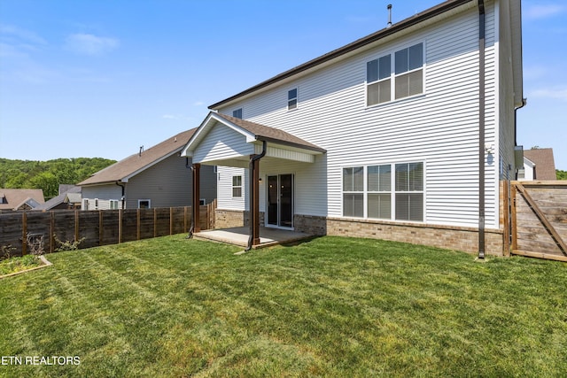 back of house featuring a fenced backyard, a patio, a yard, and brick siding