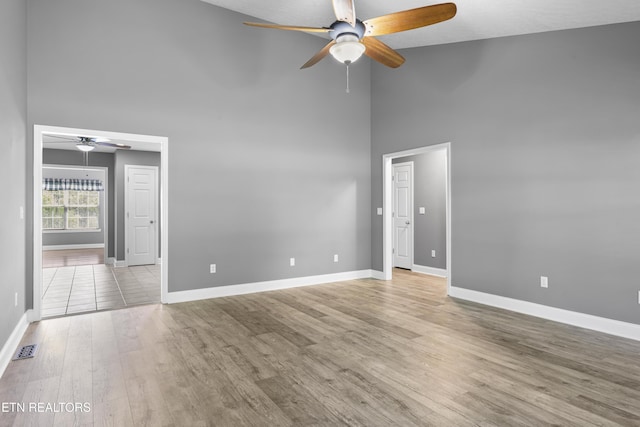 unfurnished room with ceiling fan, visible vents, wood finished floors, high vaulted ceiling, and baseboards