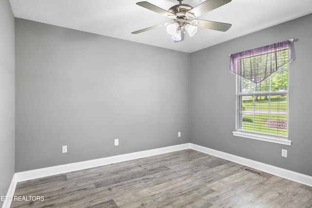 spare room featuring baseboards, wood finished floors, and visible vents