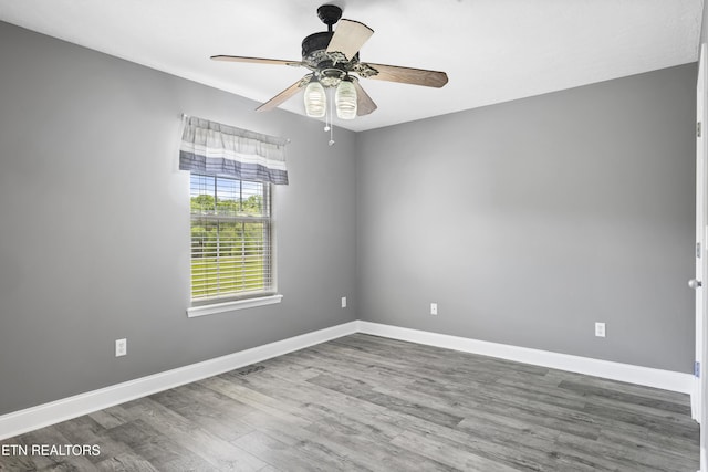 empty room with baseboards, a ceiling fan, wood finished floors, and visible vents