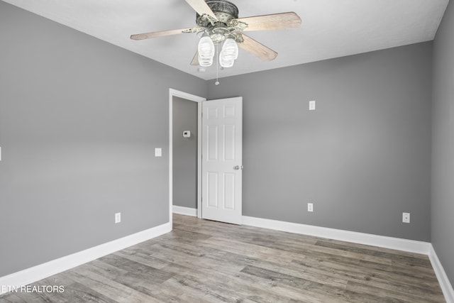 spare room with baseboards, ceiling fan, and wood finished floors