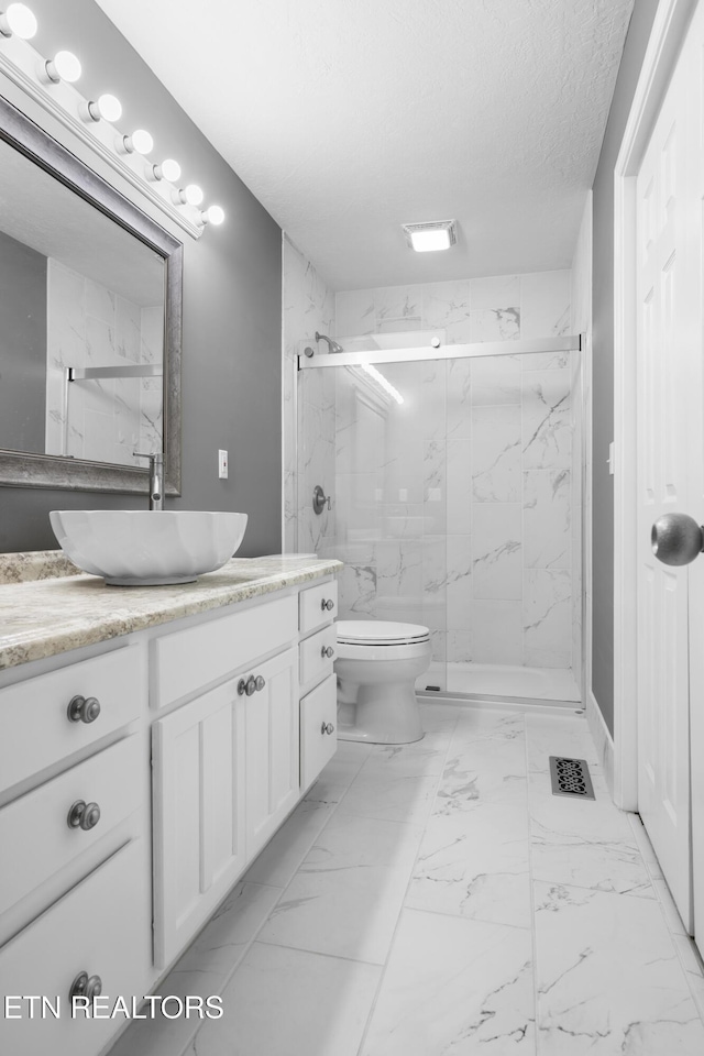 full bath with visible vents, vanity, toilet, marble finish floor, and a marble finish shower