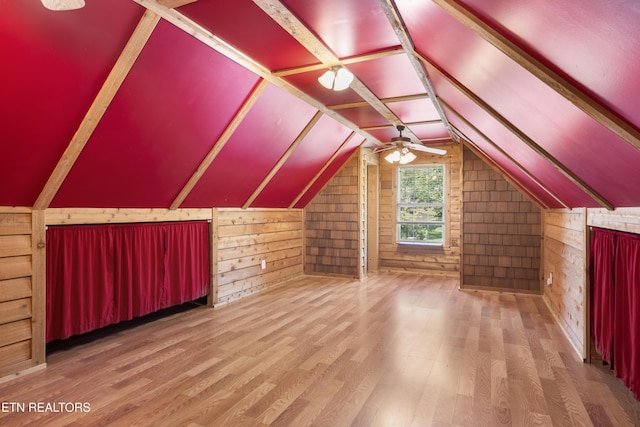bonus room with ceiling fan, vaulted ceiling, wood walls, and wood finished floors
