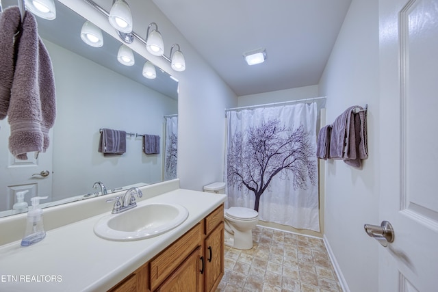 bathroom featuring stone finish flooring, curtained shower, vanity, baseboards, and toilet