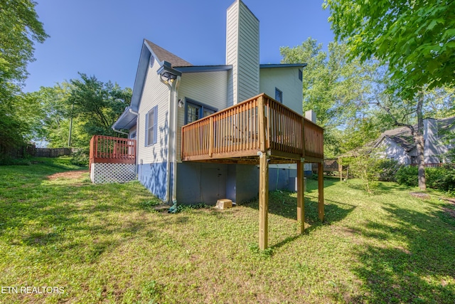rear view of house with a lawn, a wooden deck, and a chimney
