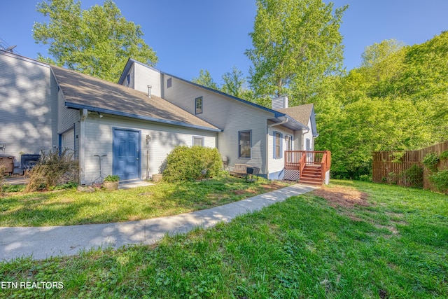 rear view of house featuring fence, a chimney, and a yard