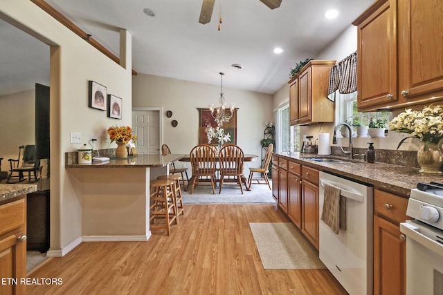 kitchen with a kitchen breakfast bar, brown cabinetry, dishwasher, a sink, and light wood finished floors
