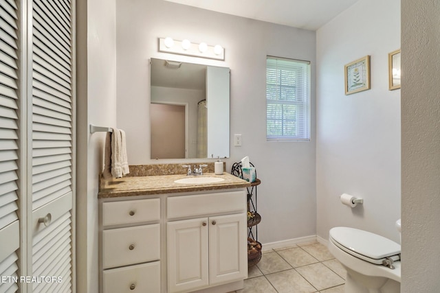 bathroom with tile patterned flooring, vanity, toilet, baseboards, and a closet