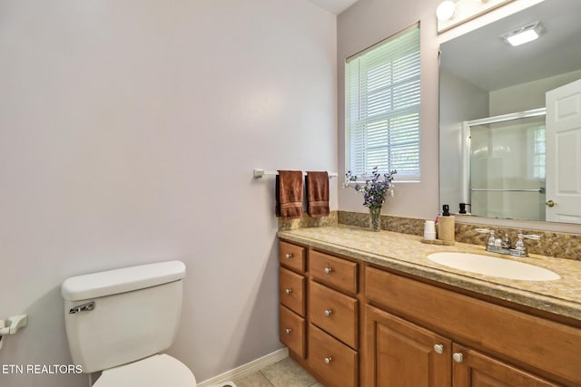 bathroom with a shower stall, vanity, tile patterned floors, baseboards, and toilet