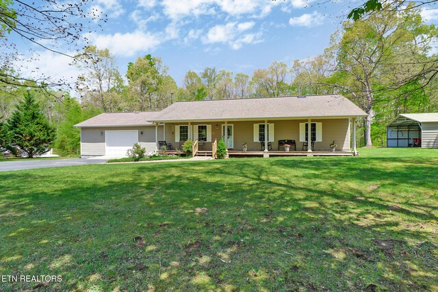 ranch-style home featuring a garage, covered porch, a front yard, and aphalt driveway