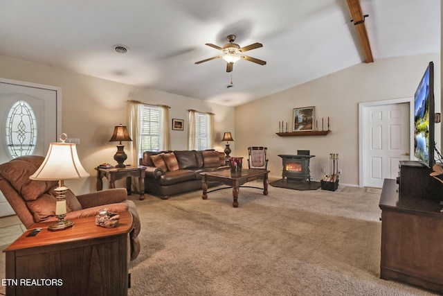 carpeted living area featuring visible vents, a wood stove, baseboards, ceiling fan, and lofted ceiling with beams