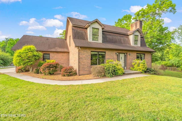 view of front of house with roof with shingles, a chimney, a front lawn, and brick siding
