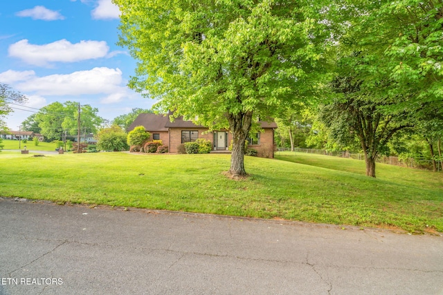 obstructed view of property with fence, a front lawn, and brick siding
