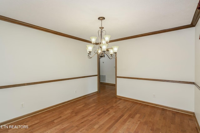 spare room with an inviting chandelier, ornamental molding, baseboards, and visible vents