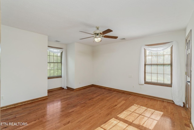 empty room featuring baseboards, ceiling fan, visible vents, and light wood-style flooring