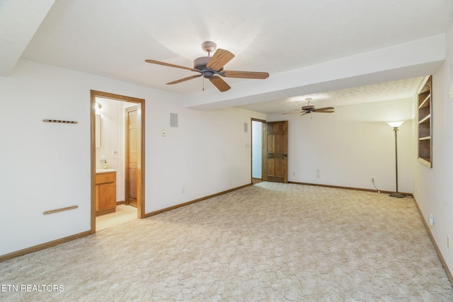 spare room with baseboards, ceiling fan, and light colored carpet